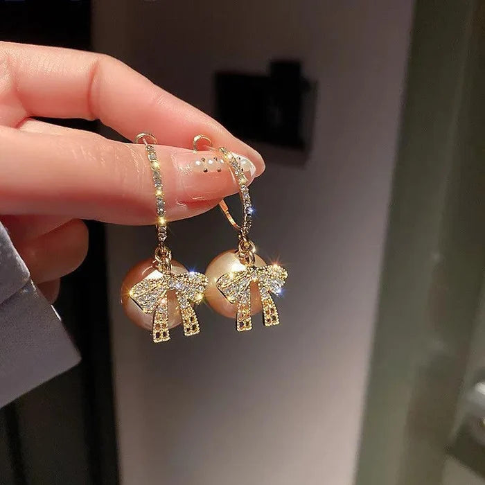 Gold hoop drop earrings with elephant charms and rhinestone bow detailing