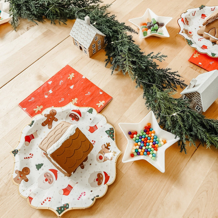 Christmas icon plates set on light wood floor, including round gingerbread design and star plate