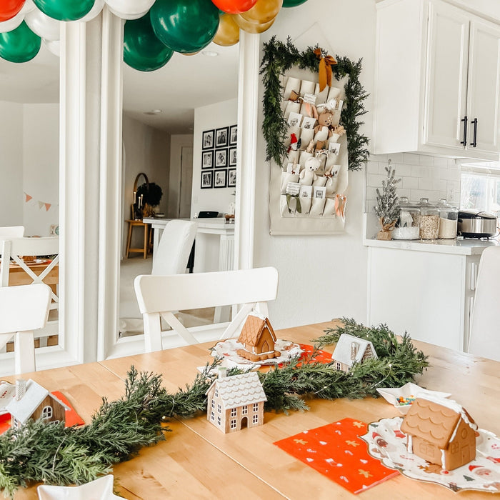 Christmas icon plates on a dining table with greenery and small house decor