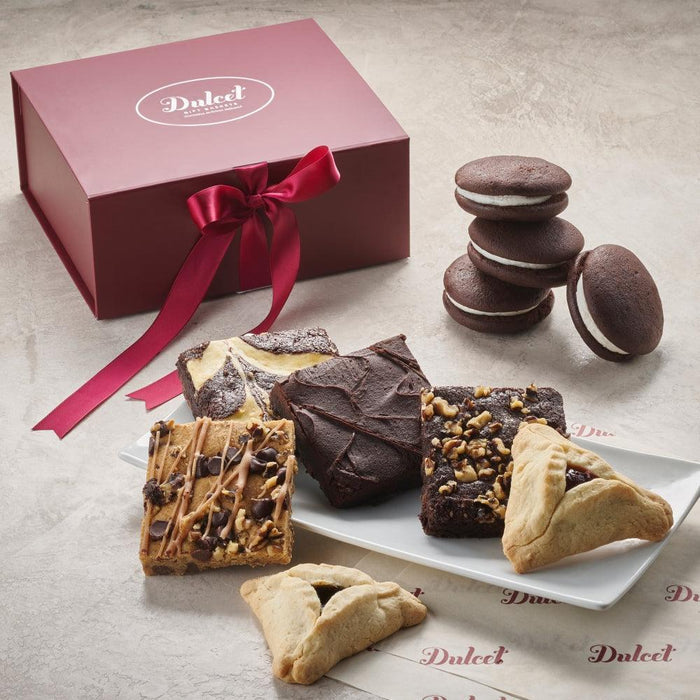Chocolate gift box with red ribbon, assorted cookies and brownies on a tray