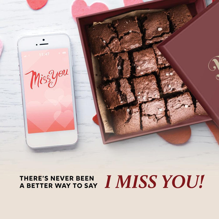 Open brownie gift box with fudgy chocolate squares beside a smartphone