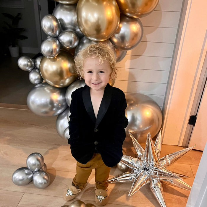 Child standing under gold and silver balloon arch with star balloons