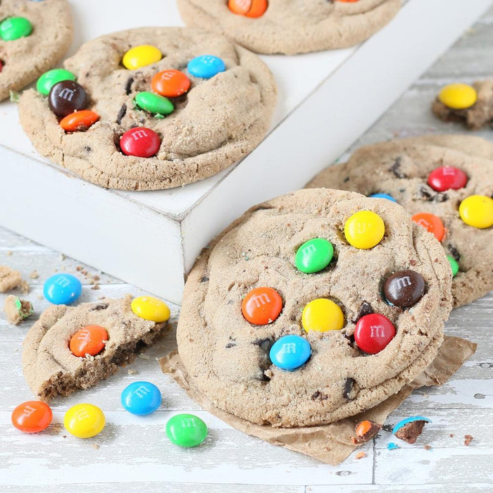Chocolate chip cookies topped with colorful candies, arranged on a white tray