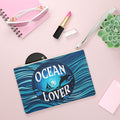 Ocean Lover clutch bag with blue wave print, round dolphin logo, white zip and strap