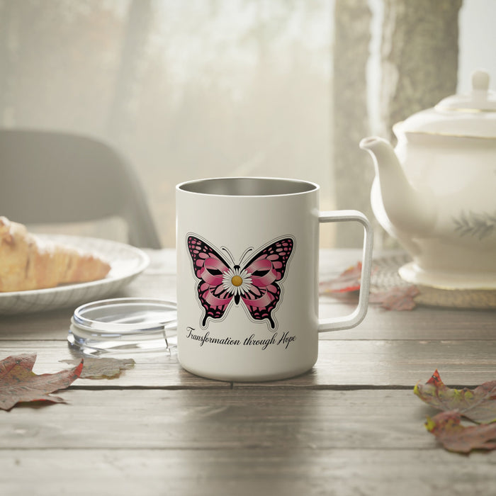 White insulated coffee mug with pink butterfly graphic and “Transformation through Hope”