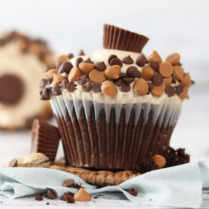 Chocolate cupcakes with caramel chips and white frosting on paper wrapper