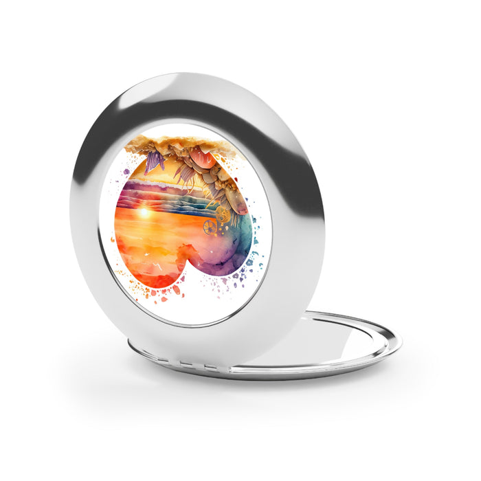 Silver glossy compact travel mirror, open with heart-shaped beach artwork on the back