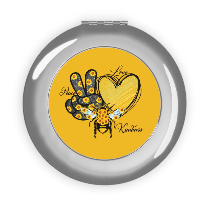Silver glossy compact travel mirror with yellow artwork and peace/love/kindness design