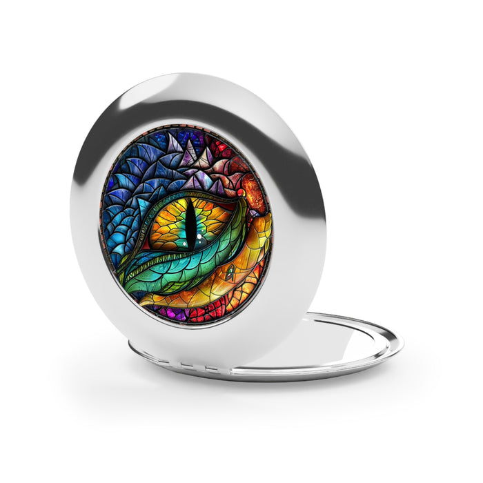 Silver round compact travel mirror with dragon eye artwork, half-open lid.