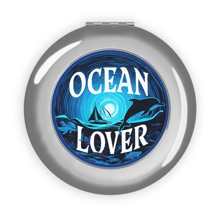 Silver round compact mirror with Ocean Lover ocean graphic and dolphins on the front