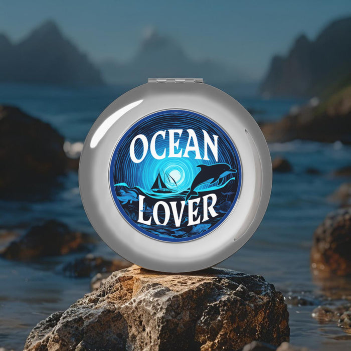 Silver round compact mirror with Ocean Lover ocean graphic and dolphins, front view
