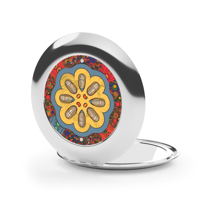 Silver glossy compact mirror open, showing colorful floral disc on round face