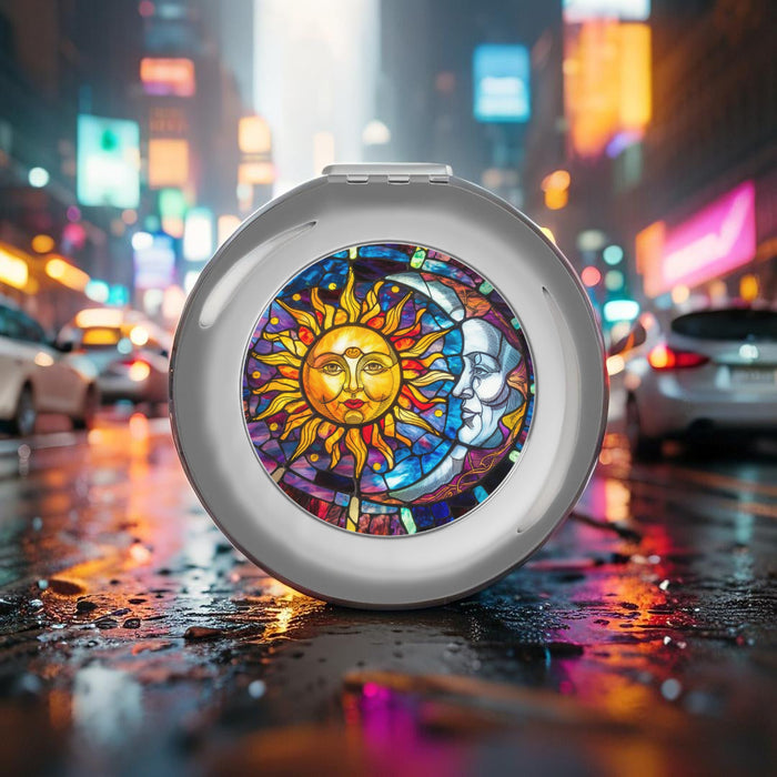 Silver glossy compact travel mirror showing round sun-and-moon artwork