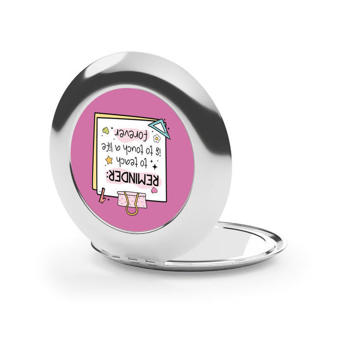 Silver glossy compact travel mirror with pink reminder insert on the back panel