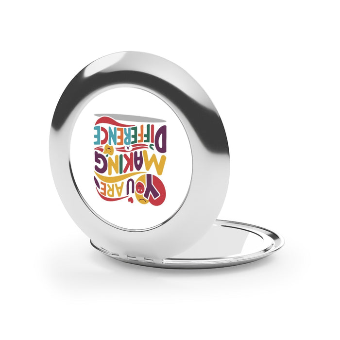 Silver glossy compact mirror open with one round mirror and logo on back cover