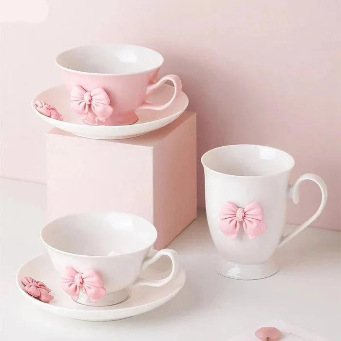Porcelain tea cup and saucer set in white with pink bow detail, handle on right