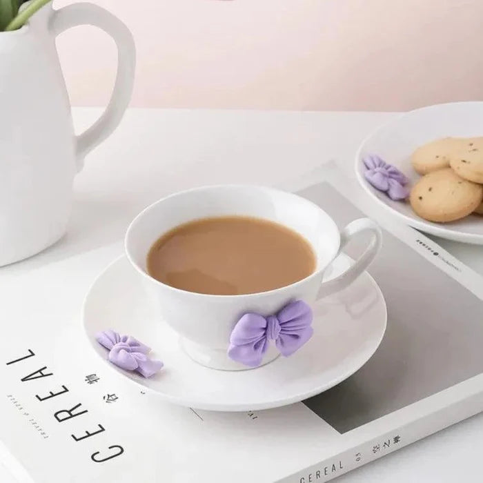 White tea cup and saucer with purple bow decoration and filled tea cup