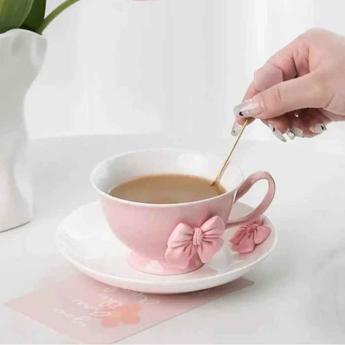 Pink tea cup and saucer pouring cup of tea, pink bow accents on front