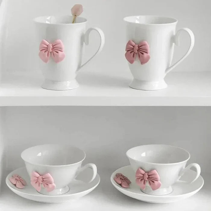 Set of two white tea cups with pink bow ornaments on saucers