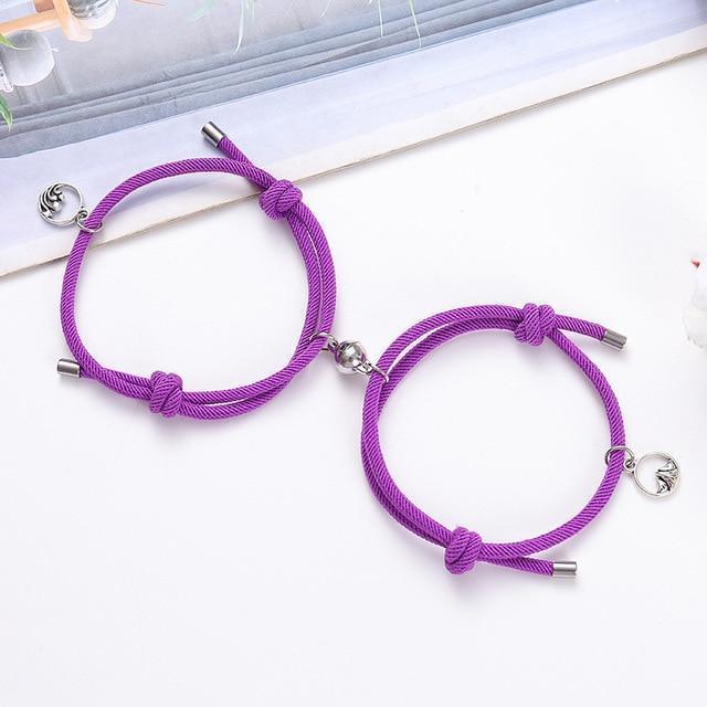 Purple braided couple attraction bracelets with small charm pendants and metal tube ends