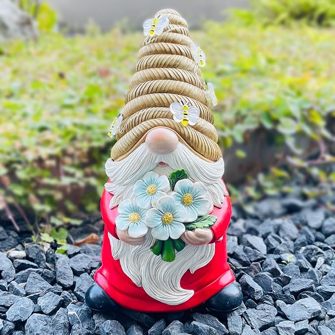 Bee-themed solar LED gnome statue on rocks, red coat, white beard, blue daisy-like flowers, unlit