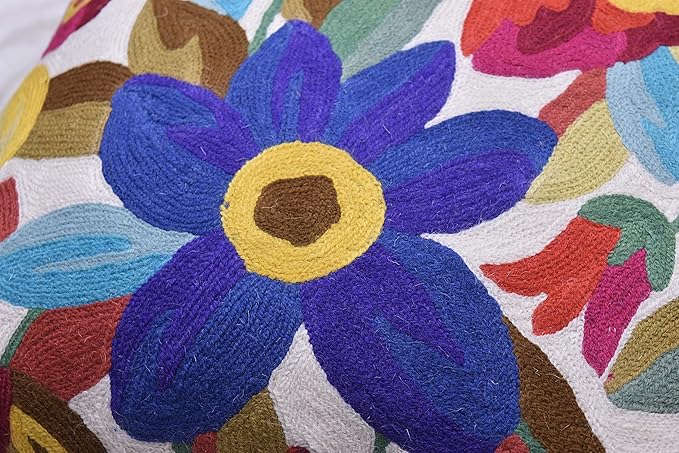 Close-up of blue floral embroidery on white pillow cover with colorful leaves