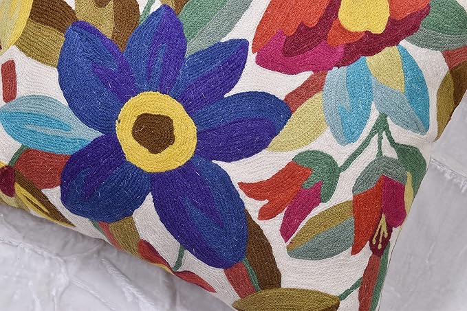 Close-up of purple and blue flower embroidery on white pillow cover with red leaves