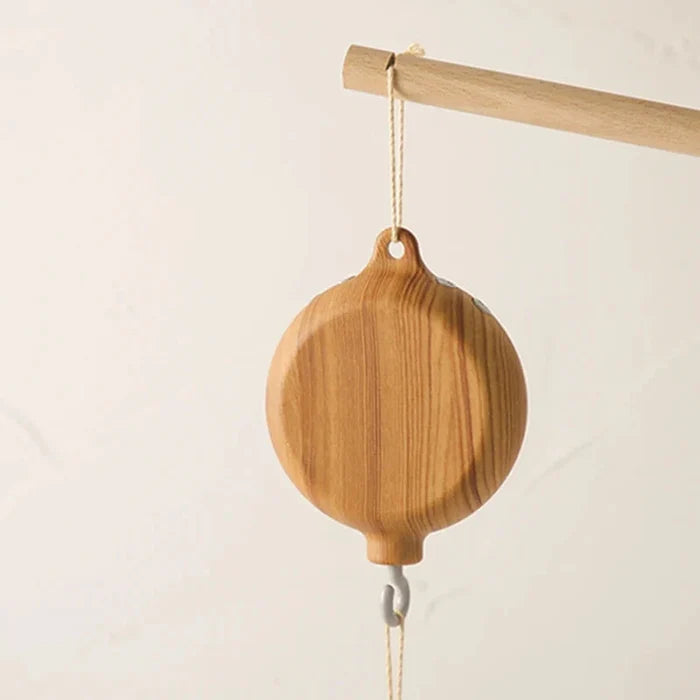 Wooden whale crib music box hanging by a string with white hook