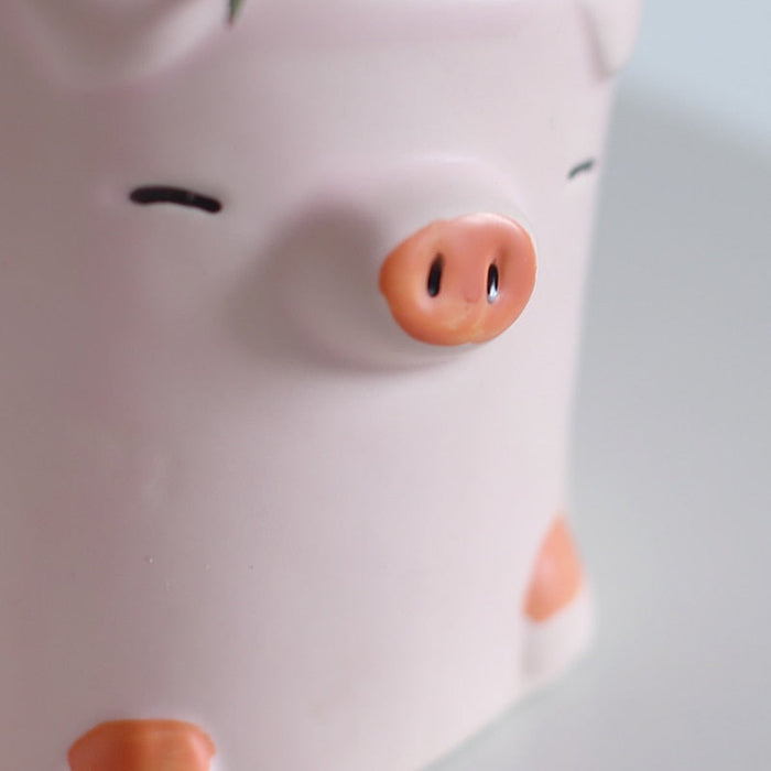 Pink pig ceramic planter close-up with orange snout and dot eyes.