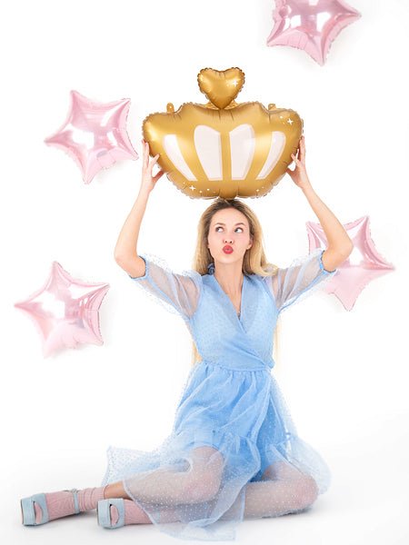 Gold crown balloon with heart topper and white cutout design, raised overhead