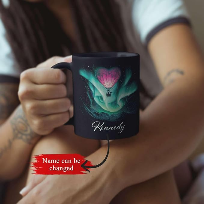 Black mug with aurora hot air balloon heart design and name Kennedy, held in hand