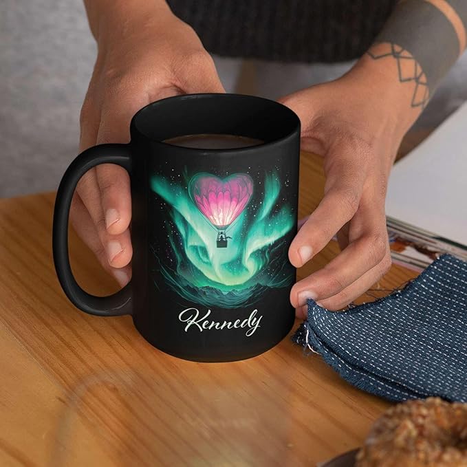 Black ceramic mug with aurora hot air balloon heart design and Kennedy, on tabletop