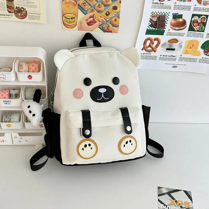 White cute bear backpack with bear-face patch, front pockets, and dangling mini bear charm