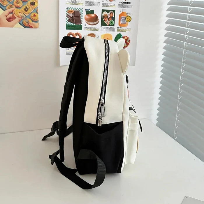 White cute bear backpack shown from the side with a top zipper and black shoulder straps