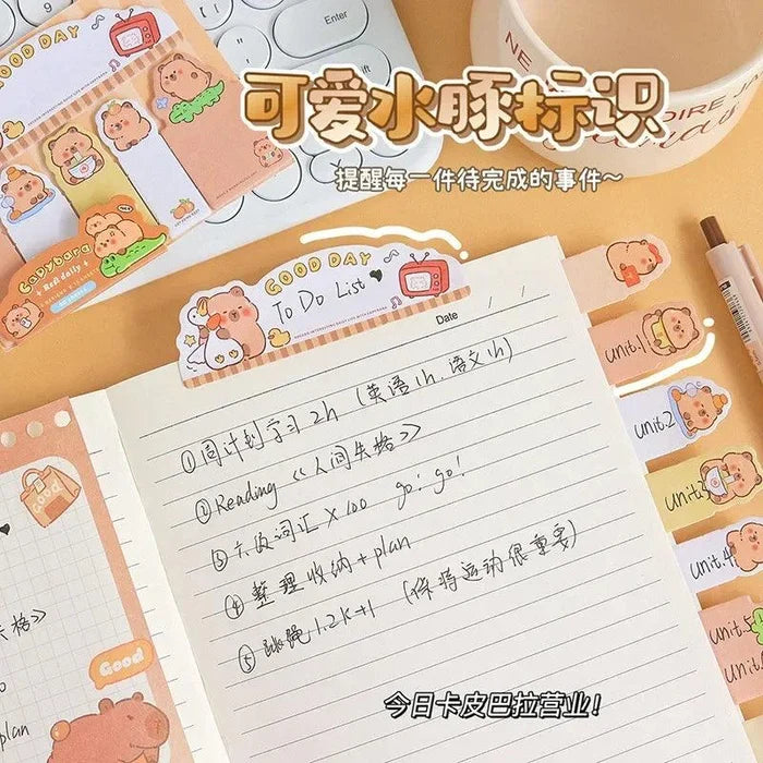 Capybara bookmark sticky notes on a lined notebook page with cartoon character icons