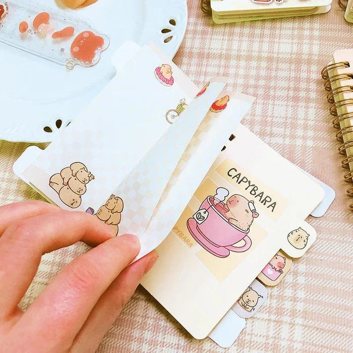 Mini notebook with capybara sticker-style cover, spiral binding, hand holding