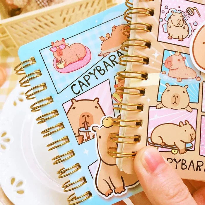 Close-up of capybara mini notebook with spiral binding and sticker-style cover art