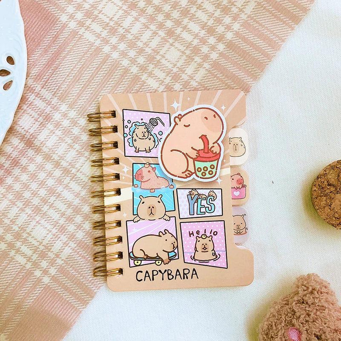 Mini notebook with capybara cartoon cover, gold spiral binding, pastel sticker labels