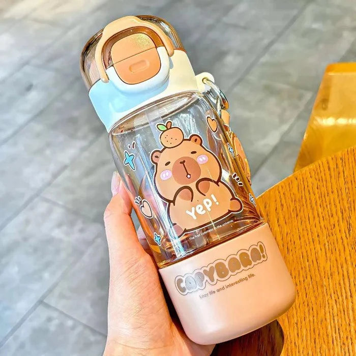 Clear capybara water bottle with peach base and flip lid, held by a hand