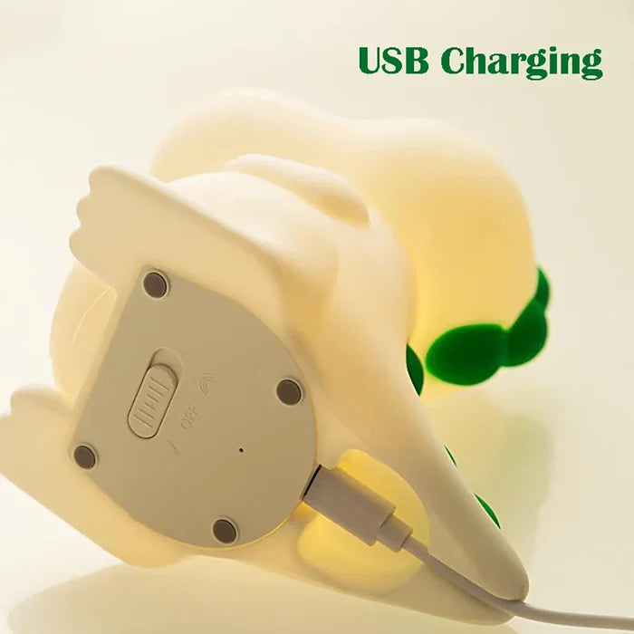 Dinosaur night light back with USB charging cable connected, green tail highlights