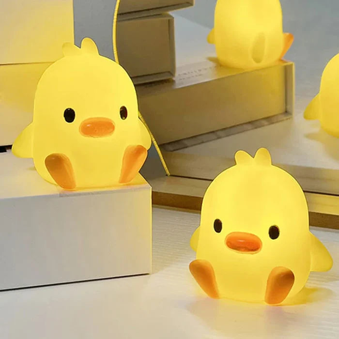 Yellow duck-shaped night light with orange beak and black eyes, sitting pose