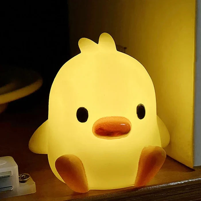 Yellow duck night light with orange beak and black eyes, glowing pose