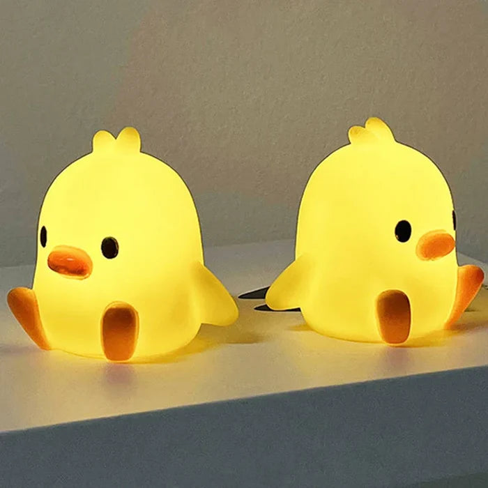 Pair of yellow duck night lights with orange beaks and black eyes on surface