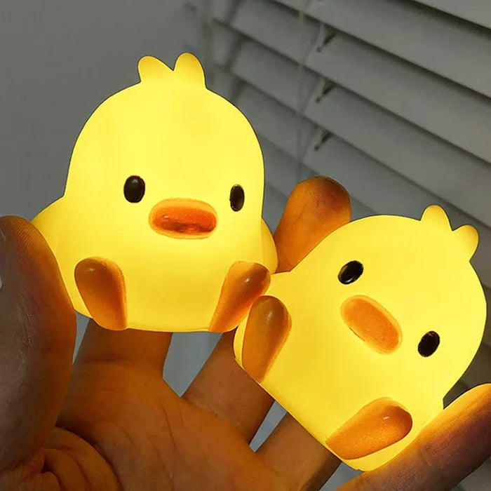 Duck night light in hands, yellow body with orange beak and black eyes, glowing
