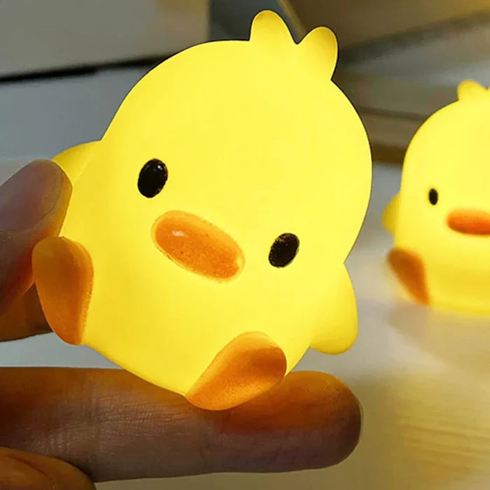 Close-up of yellow duck night light with orange beak and black eyes, glowing