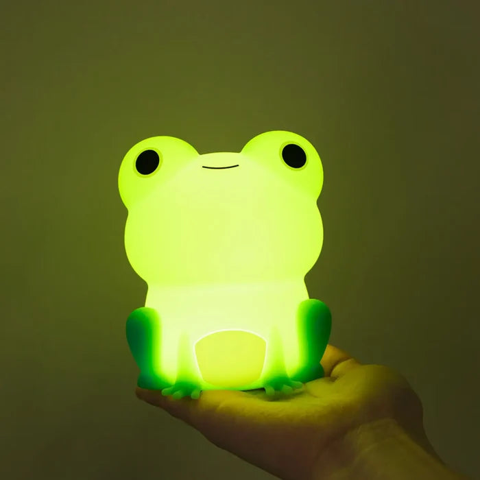 Silicone frog night light, glowing green frog held in a hand