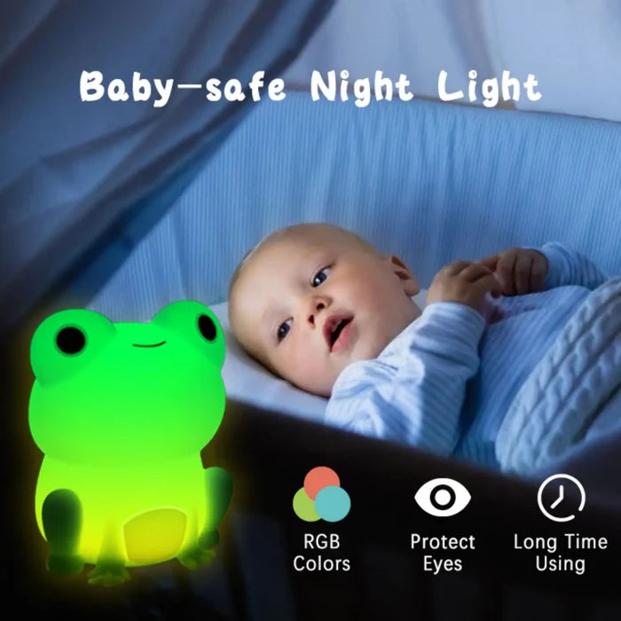 Silicone frog night light glowing green on a bed near a baby