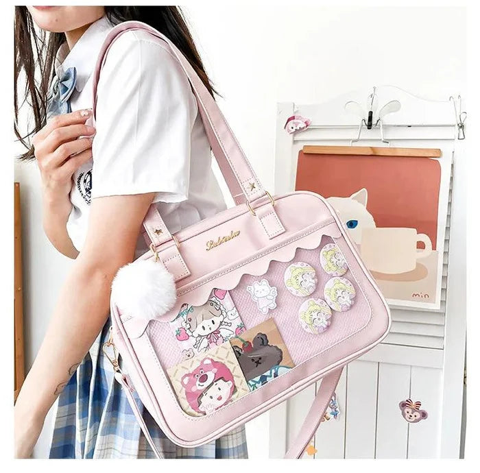 Pink Ita messenger bag worn crossbody, character patchwork window, pom-pom keychain