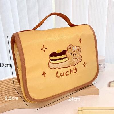 Cute makeup bag with flap front, orange fabric, bear-and-cake applique with “Lucky”
