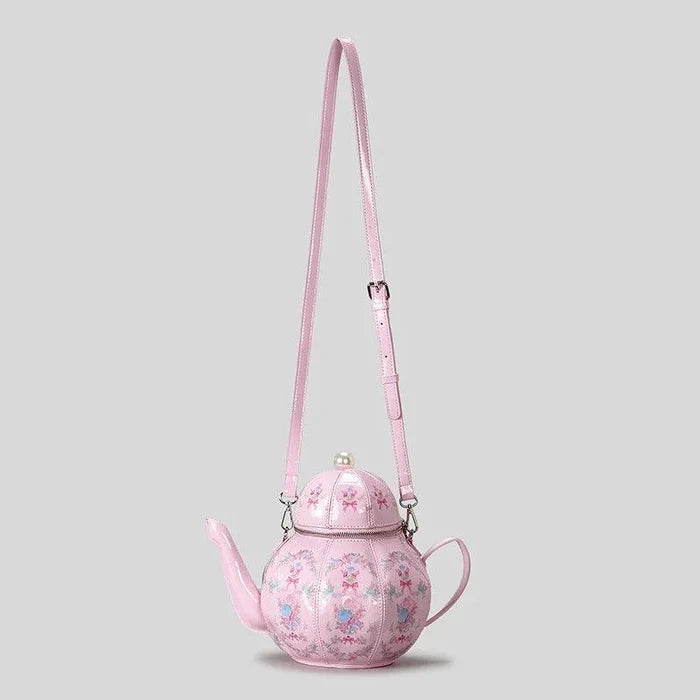 Pink teapot-shaped crossbody bag with pearl-look chain and long shoulder strap